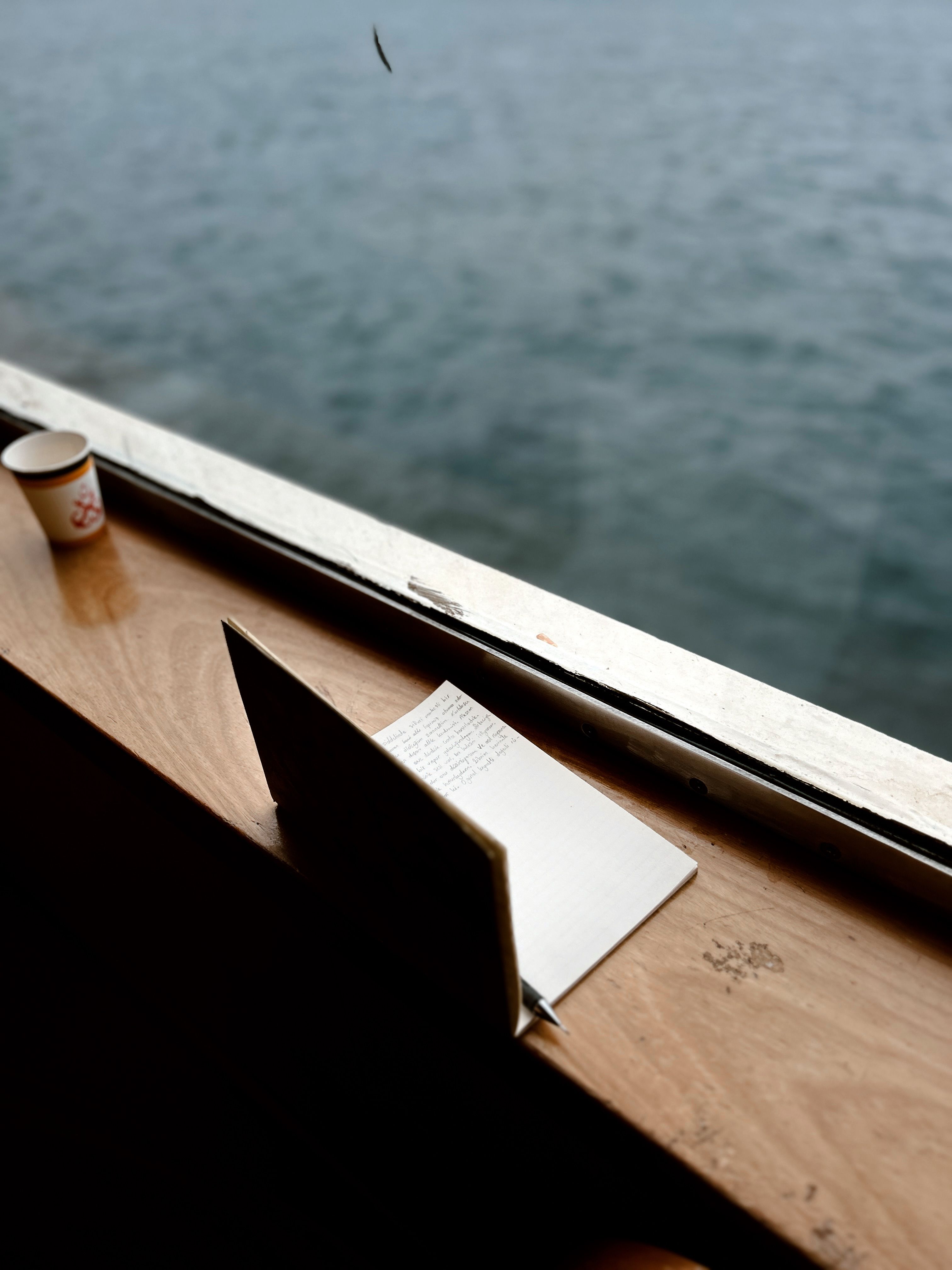 A peaceful scene of a journal and coffee cup by the window overlooking the sea.