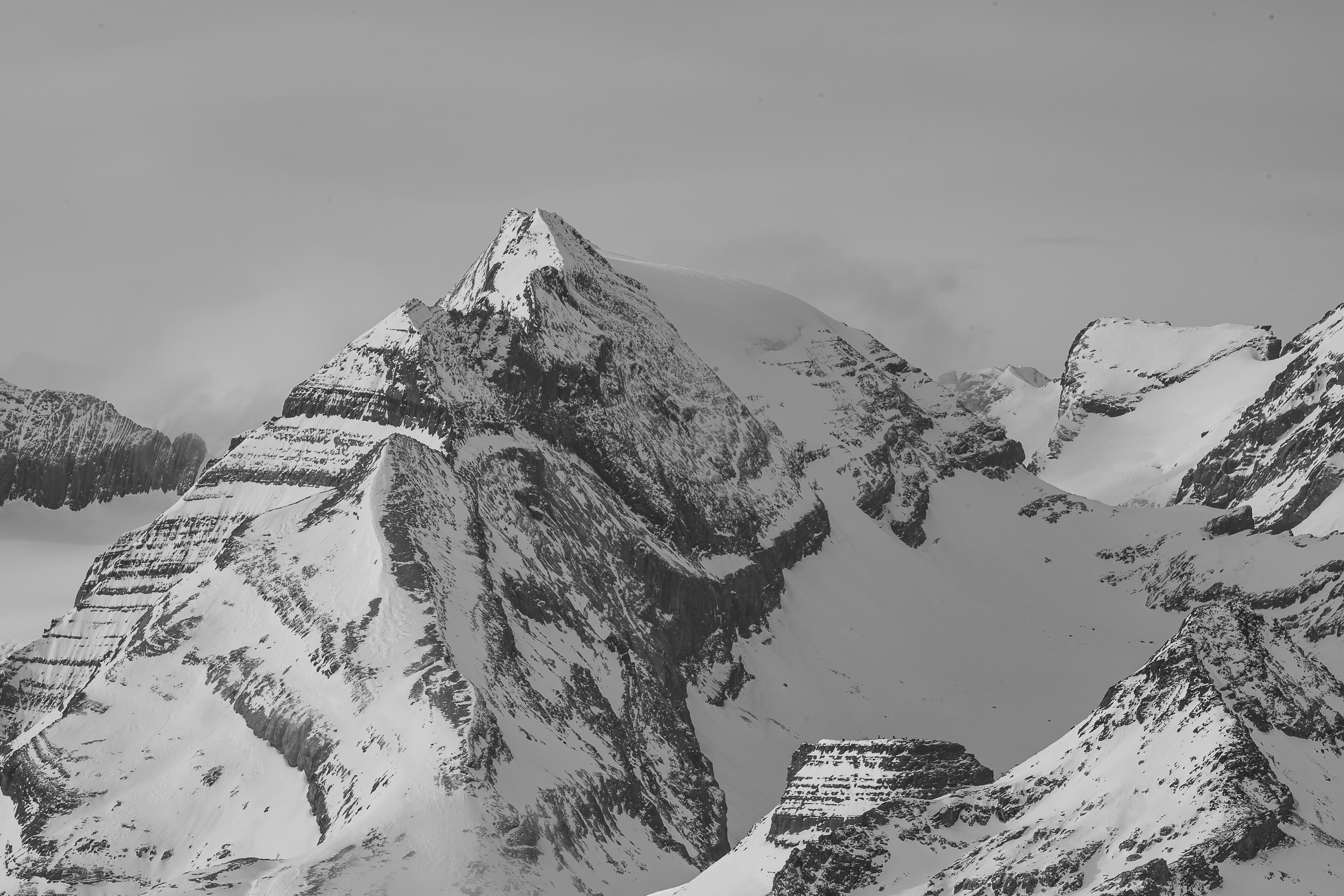Dramatic black and white photo of snow-covered Alpine peaks in Switzerland's winter wilderness.