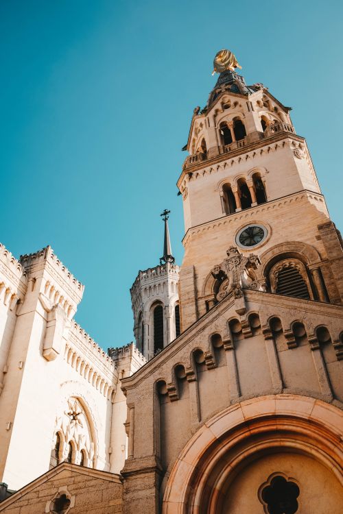 Free A beautiful architectural landmark with ornate details and arched windows against a vibrant blue sky. Stock Photo