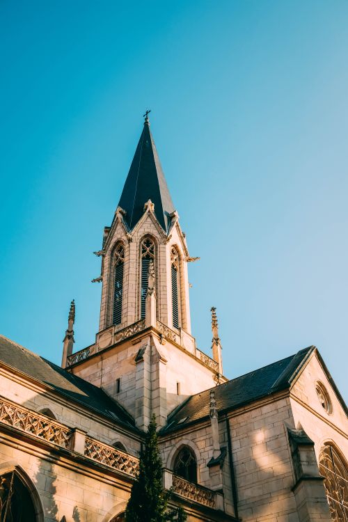 Free Elegant church with prominent spire reaching into a clear blue sky, showcasing classic architecture. Stock Photo