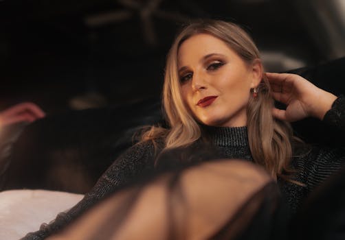 Charming woman with long hair in an elegant outfit reclining comfortably indoors, exuding confidence.