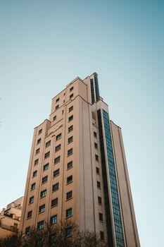 一座现代摩天大楼以低角度视角映衬在清澈的蓝天下，代表着城市建筑