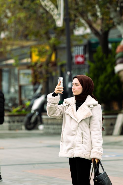 Free Woman wearing a hijab takes a selfie in a bustling city street. Stock Photo