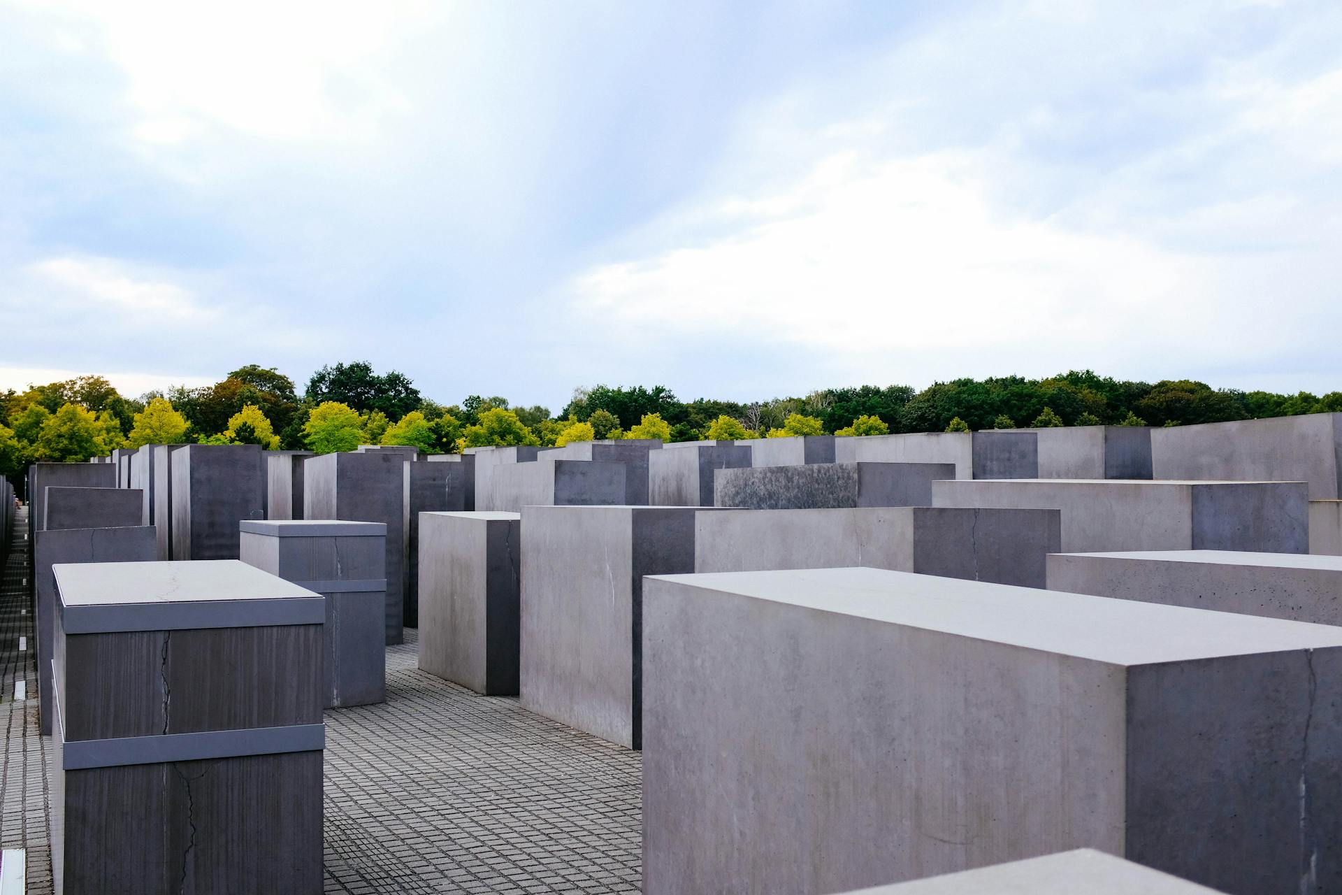 Depicts the geometric concrete blocks of the Holocaust Memorial outdoors under a cloudy sky.