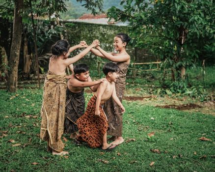 Children in traditional Indonesian attire play a classic game outdoors, showcasing cultural heritage and joyful expression.