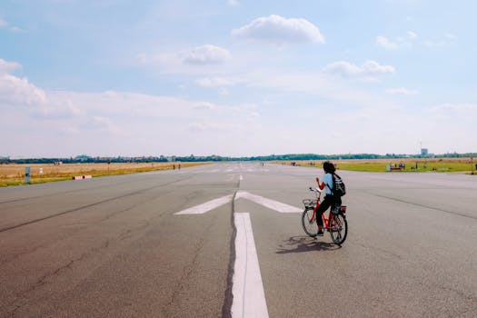 A cyclist enjoys a leisurely ride on an airport runway under a clear blue sky, highlighting peaceful outdoor urban life.