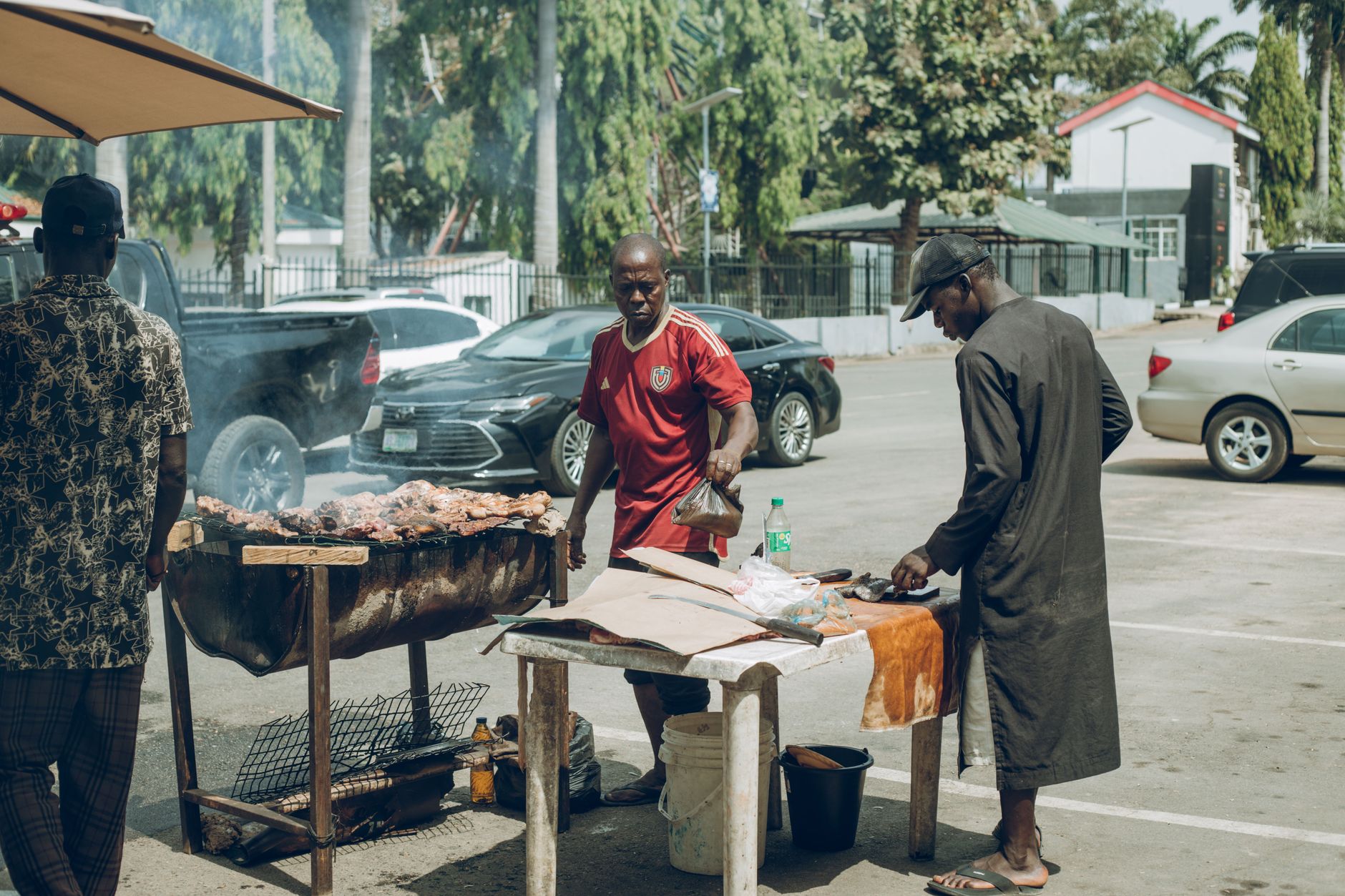 A street food vendor grilling meat in an urban outdoor setting.
