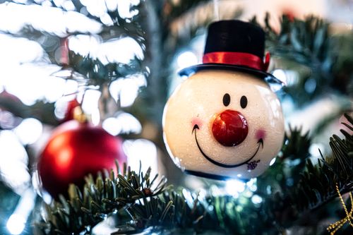 Free Charming snowman ornament with red nose and hat on a decorated Christmas tree. Stock Photo