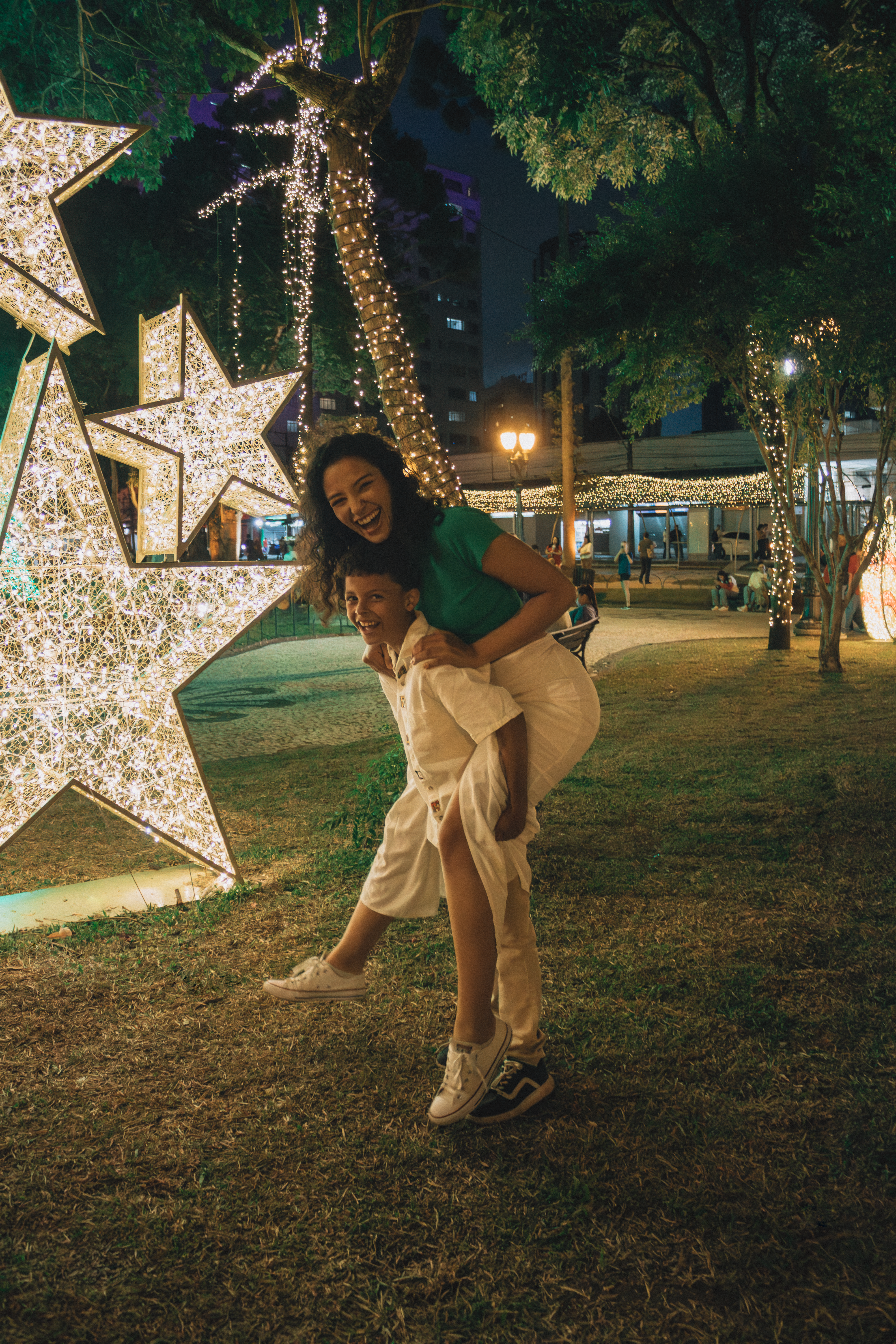 Mother and child enjoying a festive Christmas night with illuminated decorations in a park.