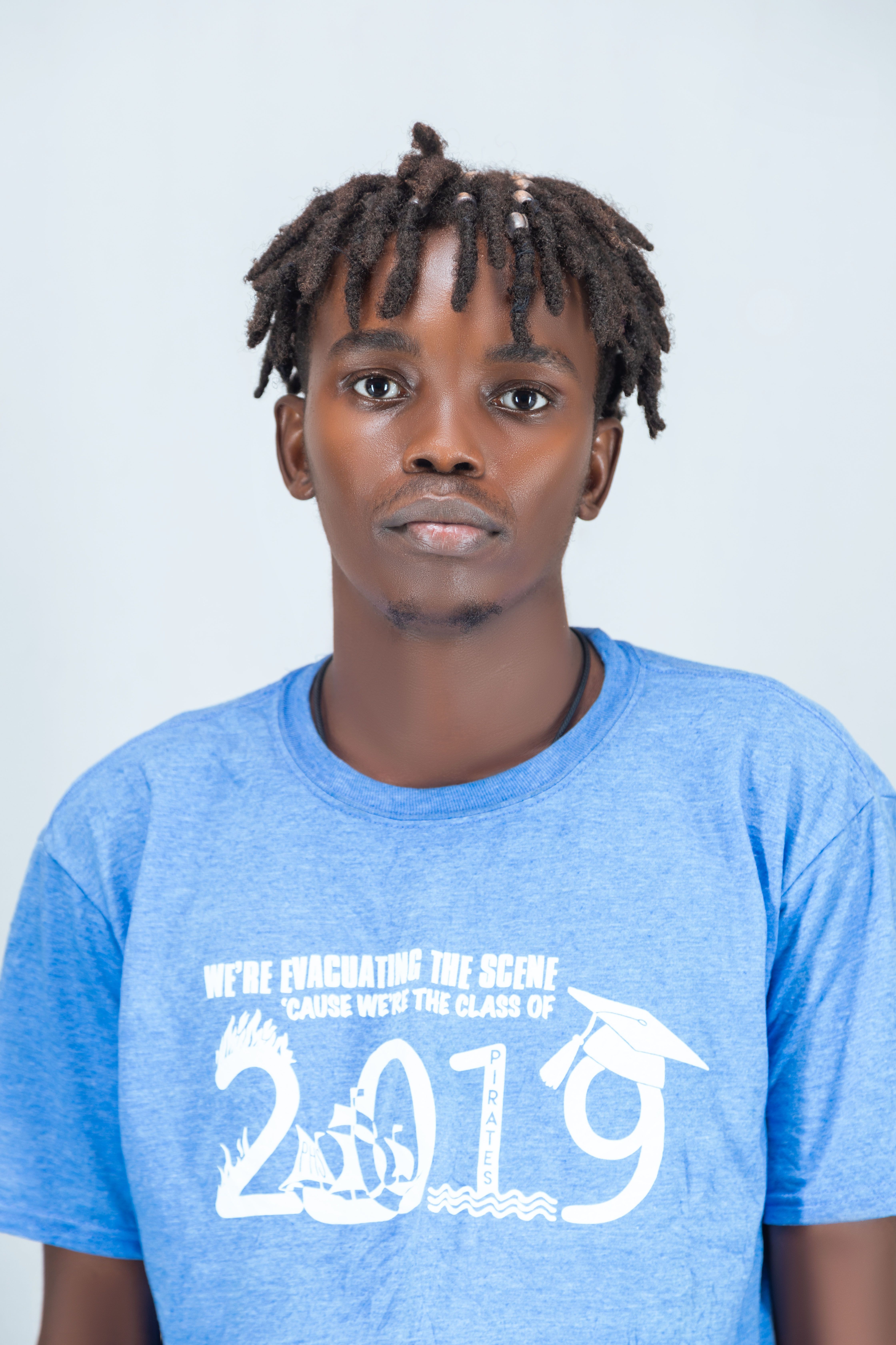 Portrait of a young man wearing a blue class of 2019 shirt, standing against a neutral background.