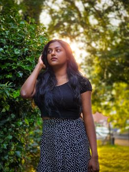 Portrait of a young woman outdoors with sunlight streaming through lush greenery.