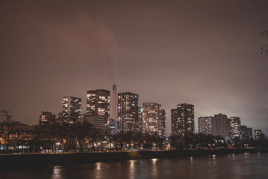 Captivating nighttime view of Paris skyline with illuminated skyscrapers along the river.