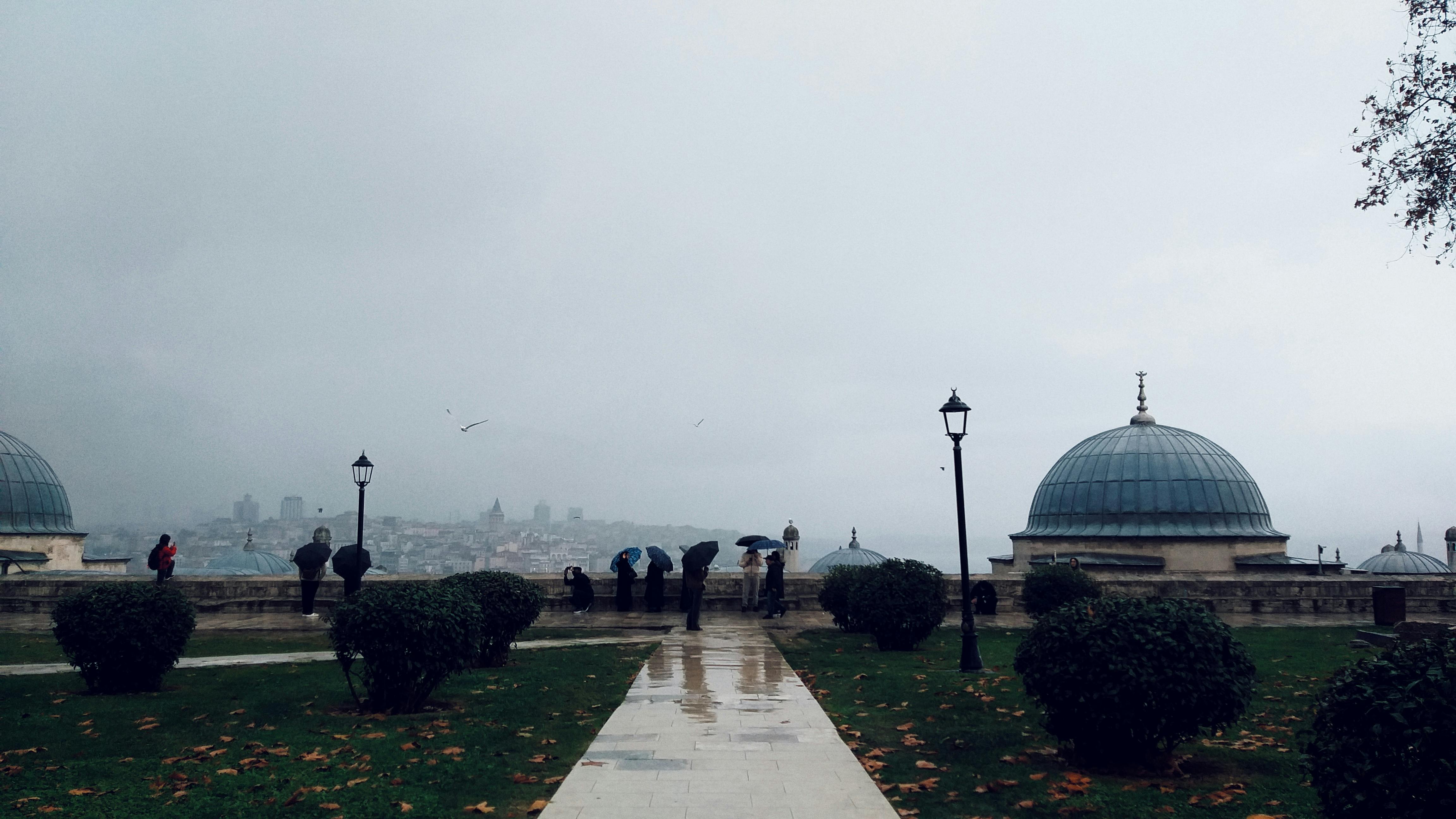People with umbrellas overlooking the Istanbul skyline on a rainy day.