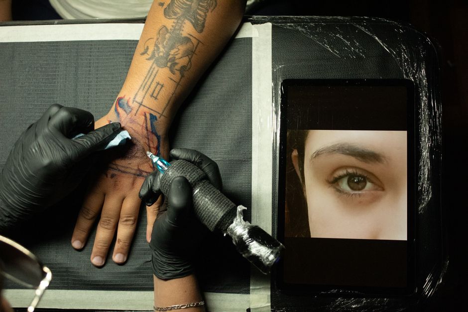 Convention tattoo artist working at a busy tattoo convention booth Convention tattoo artist working at a busy tattoo convention booth
