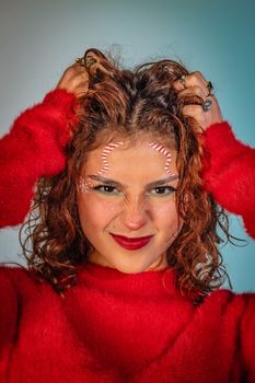 Close-up of a woman in red sweater with festive makeup, bright lipstick, and curly hair.