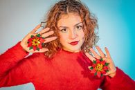 Portrait of a woman in red with poinsettia accessories, celebrating holiday spirit.