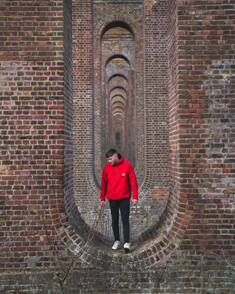 Man In Red Jacket Standing On Brick Wall