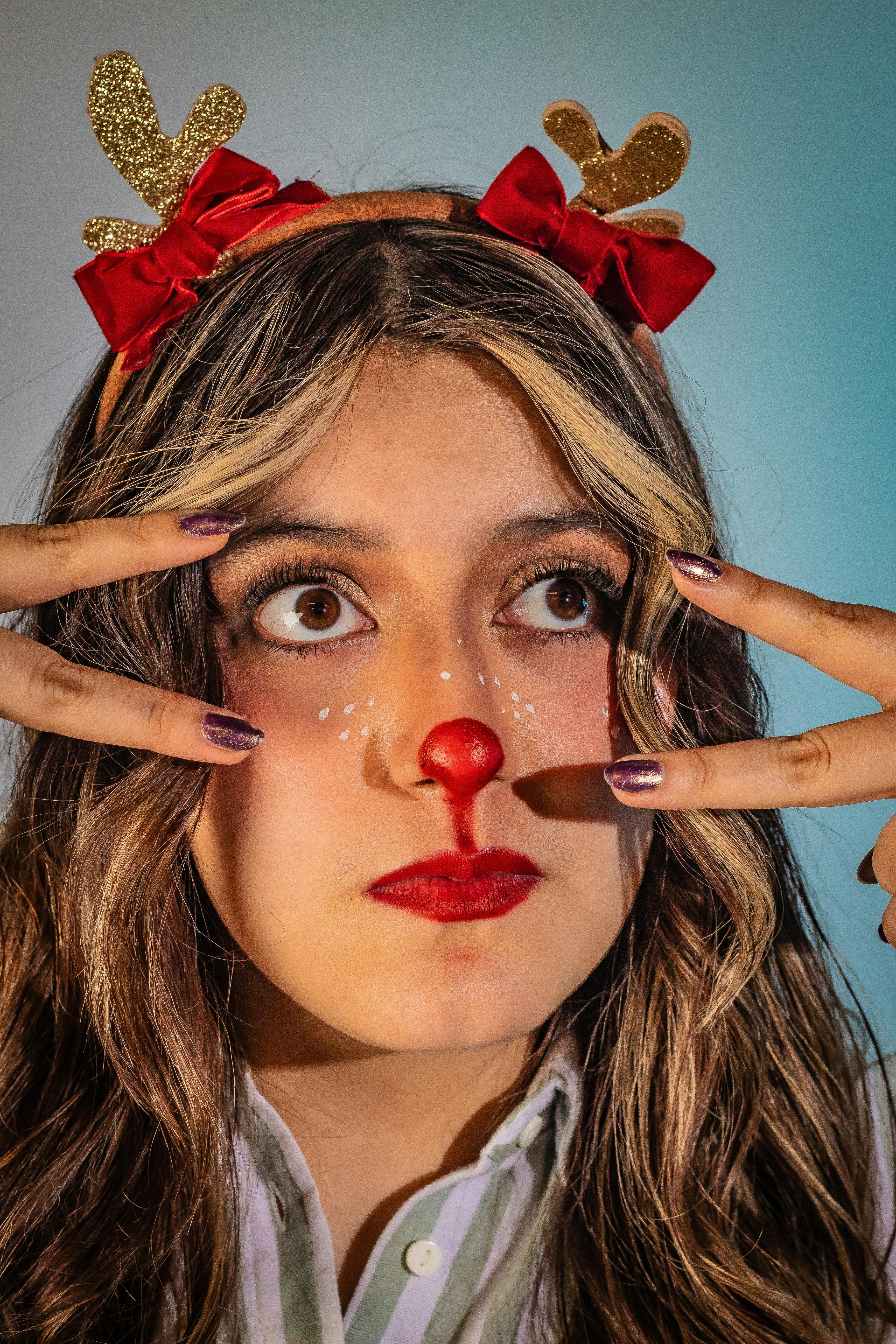 De franc Una dona posa amb una diadema de banyes de ren divertida i maquillatge festiu. Foto d'estoc