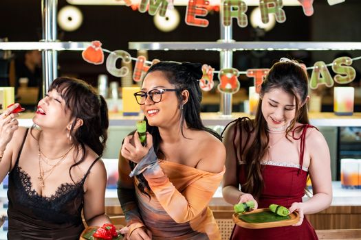 Three young women enjoying Christmas treats together in Jakarta, embracing the festive spirit.