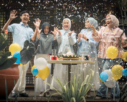 Happy family celebrating outdoors with balloons and confetti in Jawa Barat, Indonesia.