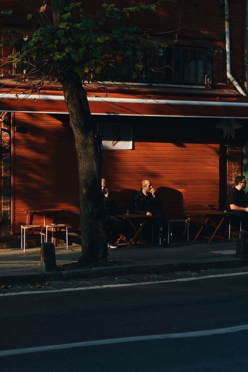 Free Men enjoy a quiet moment at an outdoor cafe at sunset. Urban city life. Stock Photo