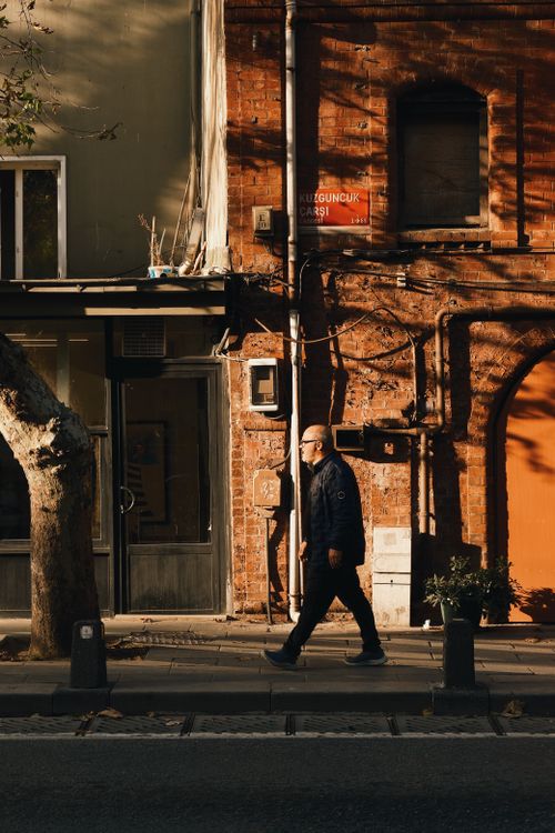 Free Man walking past a brick building in Kuzguncuk, Istanbul, during daylight. Stock Photo