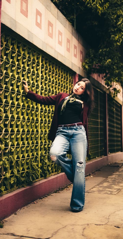 Free Casually dressed woman leans against a patterned wall outdoors, exuding confidence and style. Stock Photo