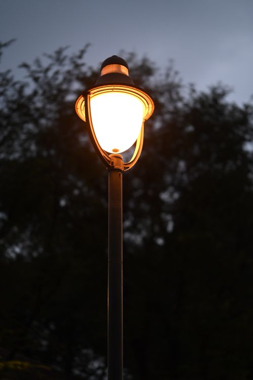 Free A glowing street lamp lights up against a dark evening sky, creating a warm ambiance. Stock Photo