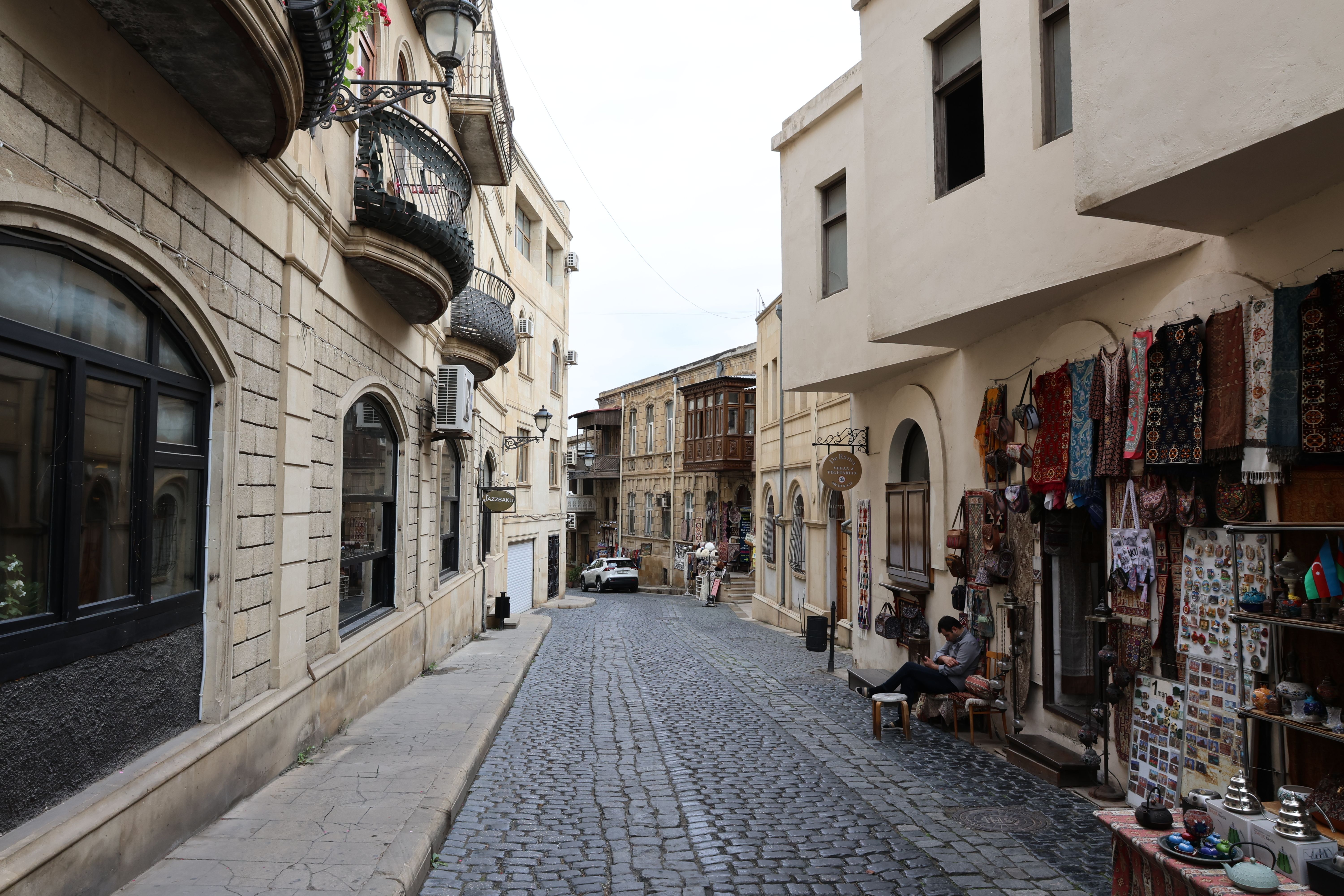 Explore a quaint cobblestone street lined with traditional architecture and market stalls in an old town setting.