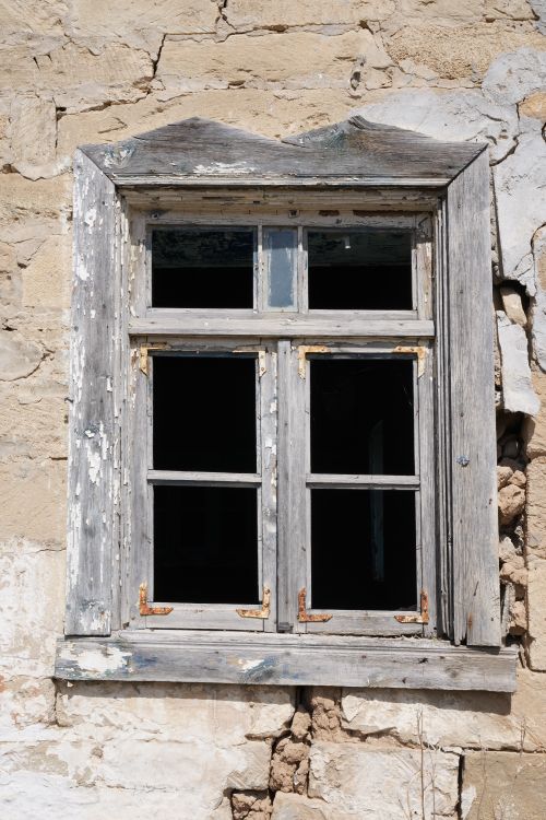 Free A weathered wooden window set in a crumbling stone wall under bright sunlight. Stock Photo