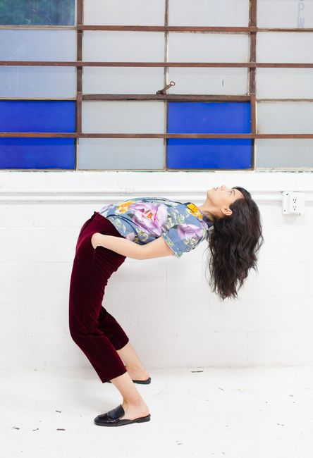 Young woman in casual wear striking a pose indoors against a multicolored window.