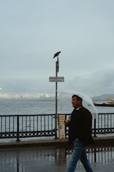 A man with an umbrella walks by the Bosphorus on a rainy day in Istanbul.