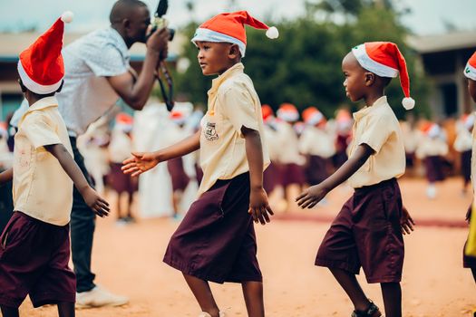 Young children in Santa hats taking part in a joyful Christmas event outdoors.