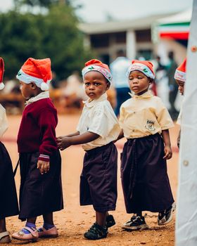 Group of young children wearing Santa hats at an outdoor Christmas event.