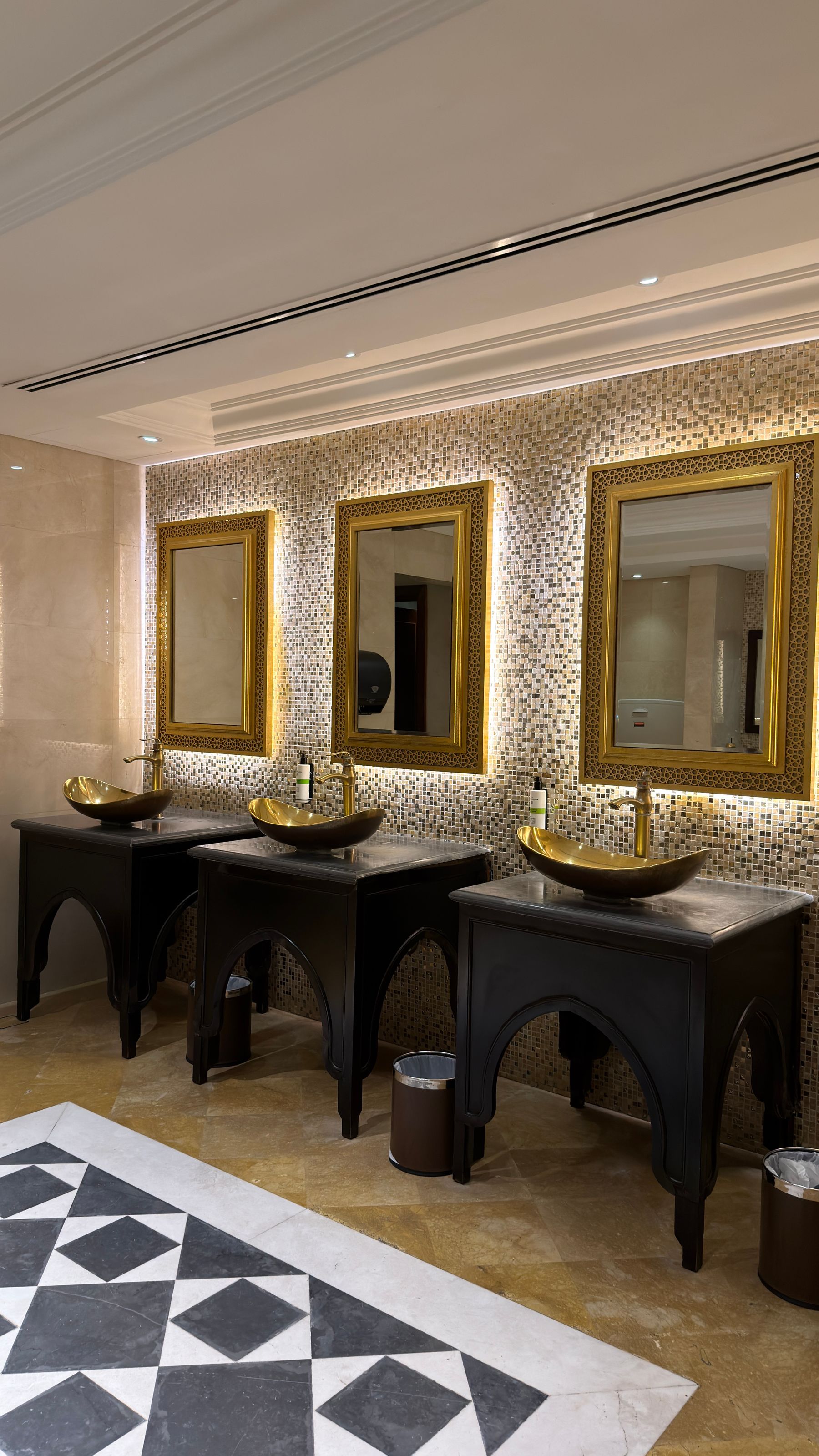 Symmetrical bathroom vanity with gold mirrors, vessel sinks and geometric flooring