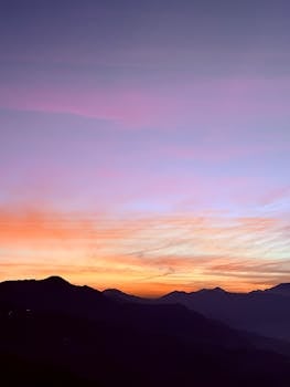 Dramatic sunset sky with vivid colors over silhouetted mountains.