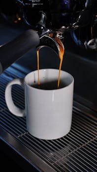 Close-up of espresso machine brewing fresh coffee into a white mug in a cafe setting.