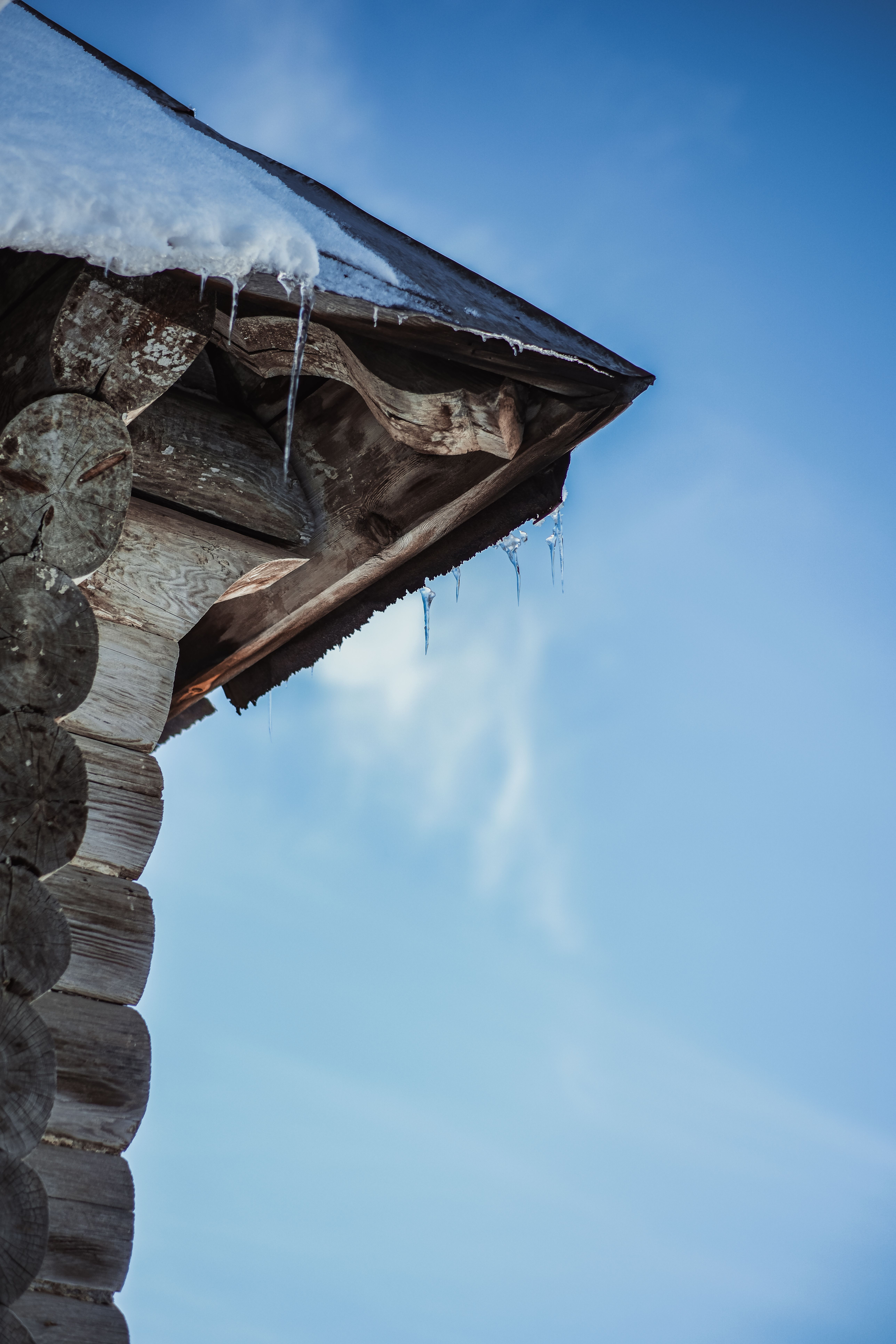 Snow-covered log cabin roof in a winter setting — illustrative roof load visual, not a listing