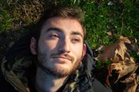 Young man lying on fall grass in sunlight