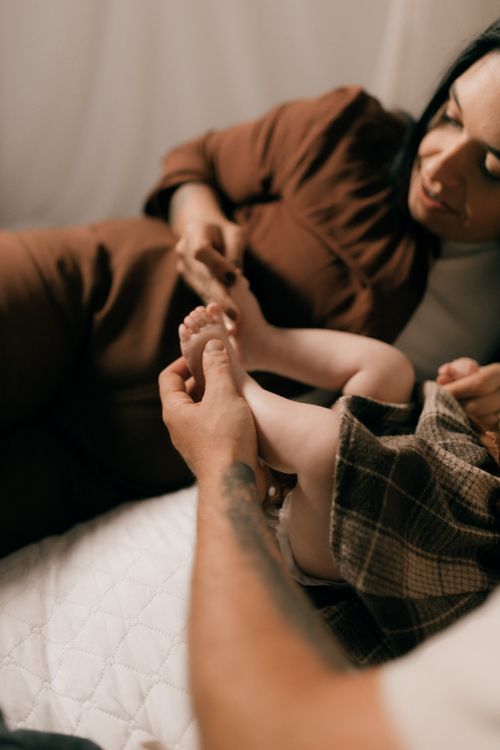 Free A tender moment of a mother holding her baby's feet in a cozy indoor setting. Stock Photo