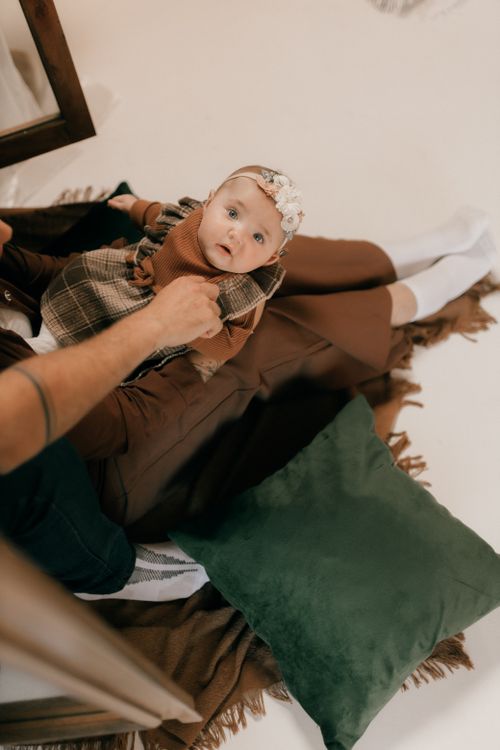 Free A baby dressed warmly lying on a blanket with family at home. Stock Photo