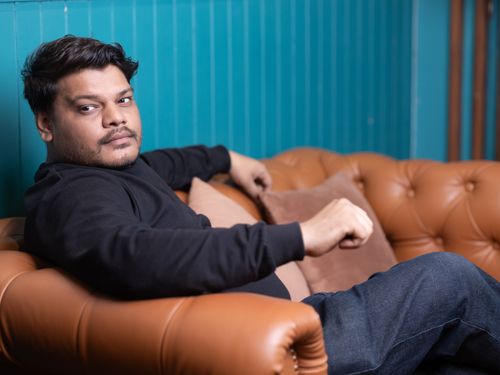 Free Man relaxing on a stylish leather couch indoors, exuding a sense of casual comfort. Stock Photo