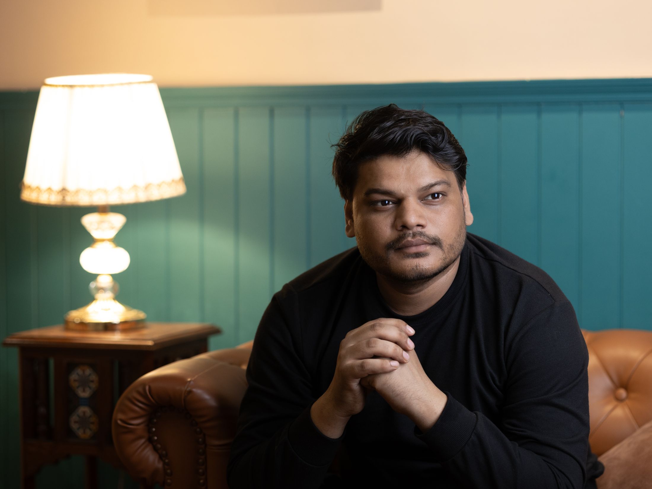 A person seated in a panelled room beside a warm table lamp. Photo by Rajat Sahu on Pexels.