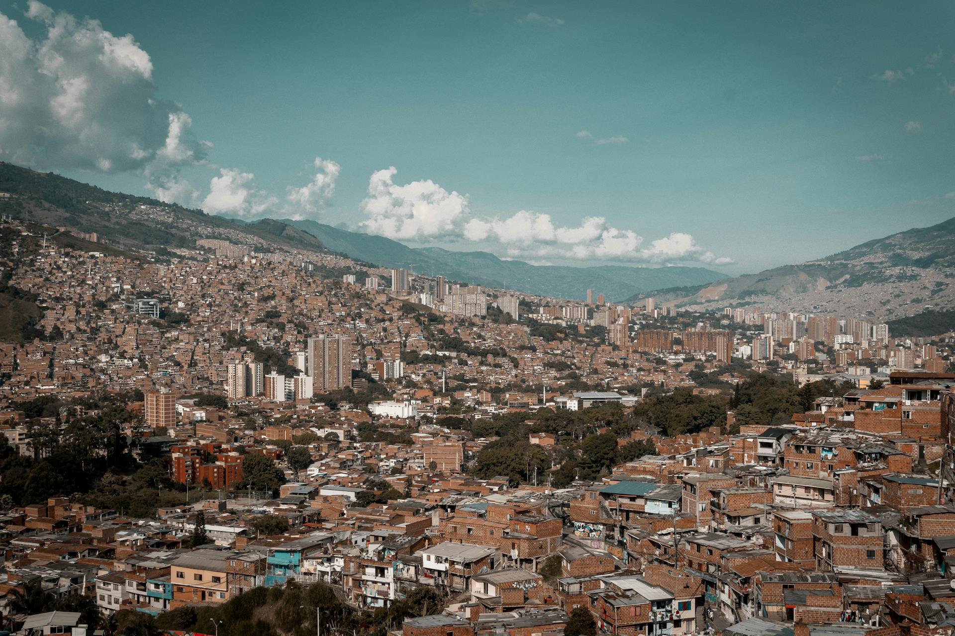 A panoramic aerial view of Medellín, showcasing its dense urban landscape against a backdrop of mountains.