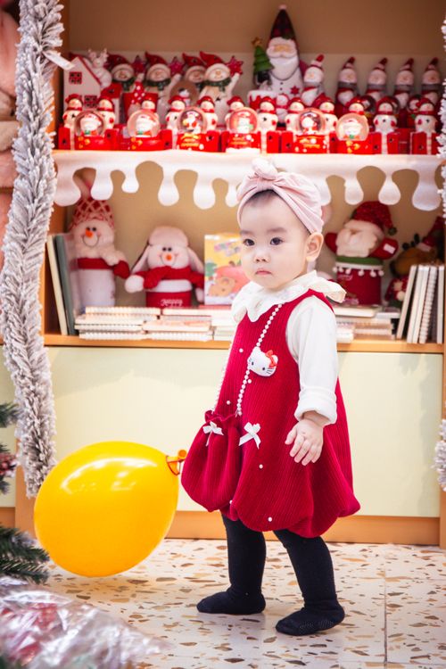 Free Adorable baby in a festive red outfit with toys and Christmas decorations around. Stock Photo