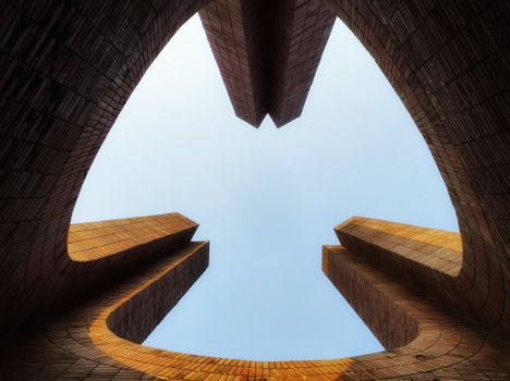 Upward view of modern brick architecture with blue sky background.