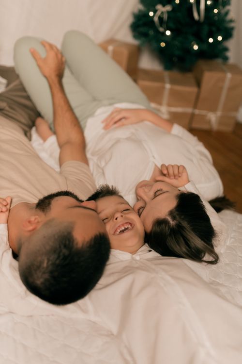 Free Family relaxing together on Christmas morning with presents under the tree. Stock Photo
