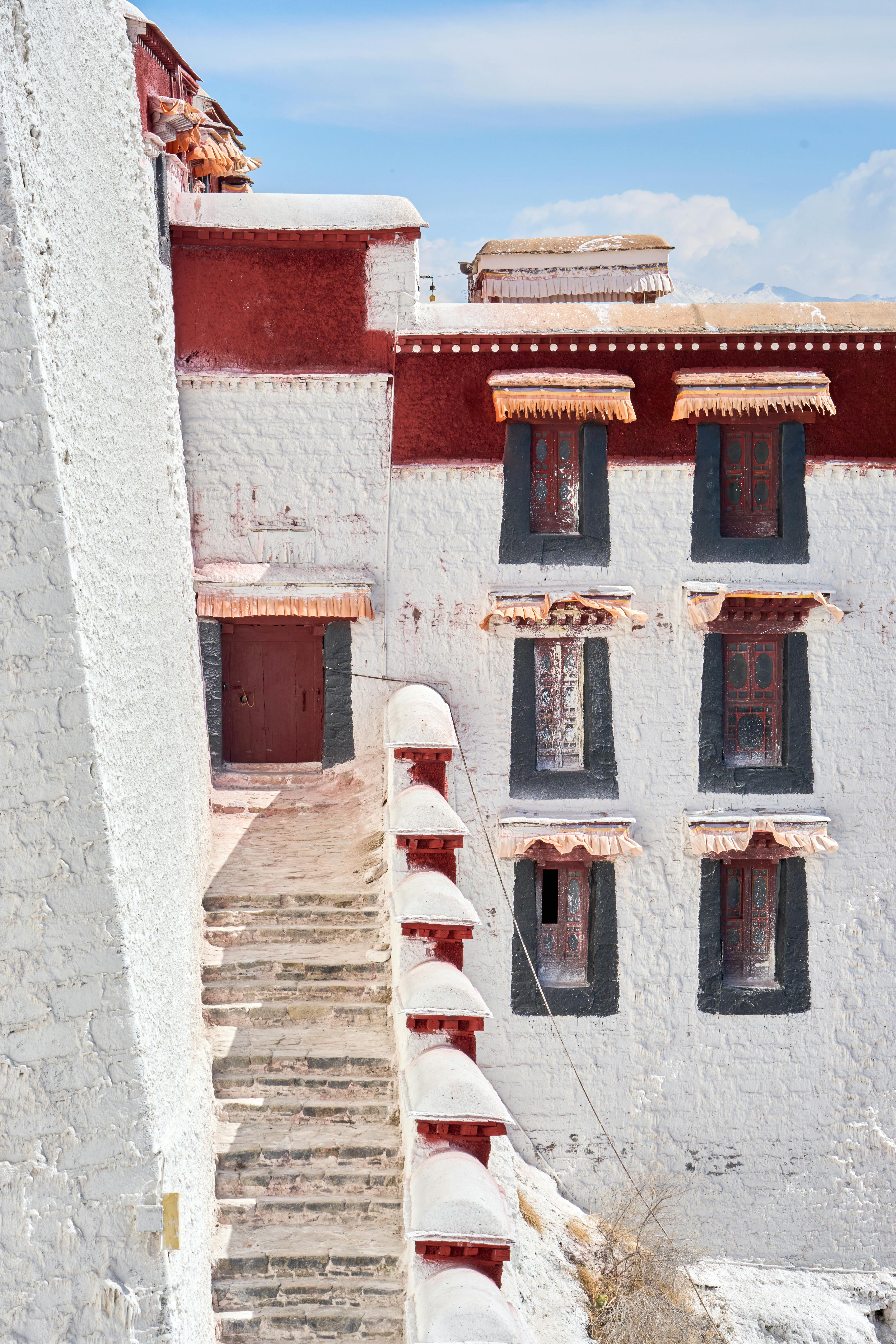 Elegant white and red architecture of a hillside monastery under a clear blue sky.