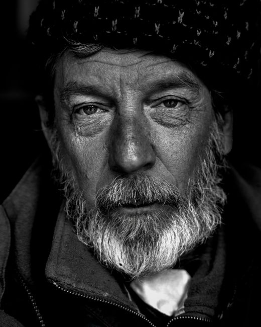 Black and white portrait of a senior man with expressive eyes and beard.