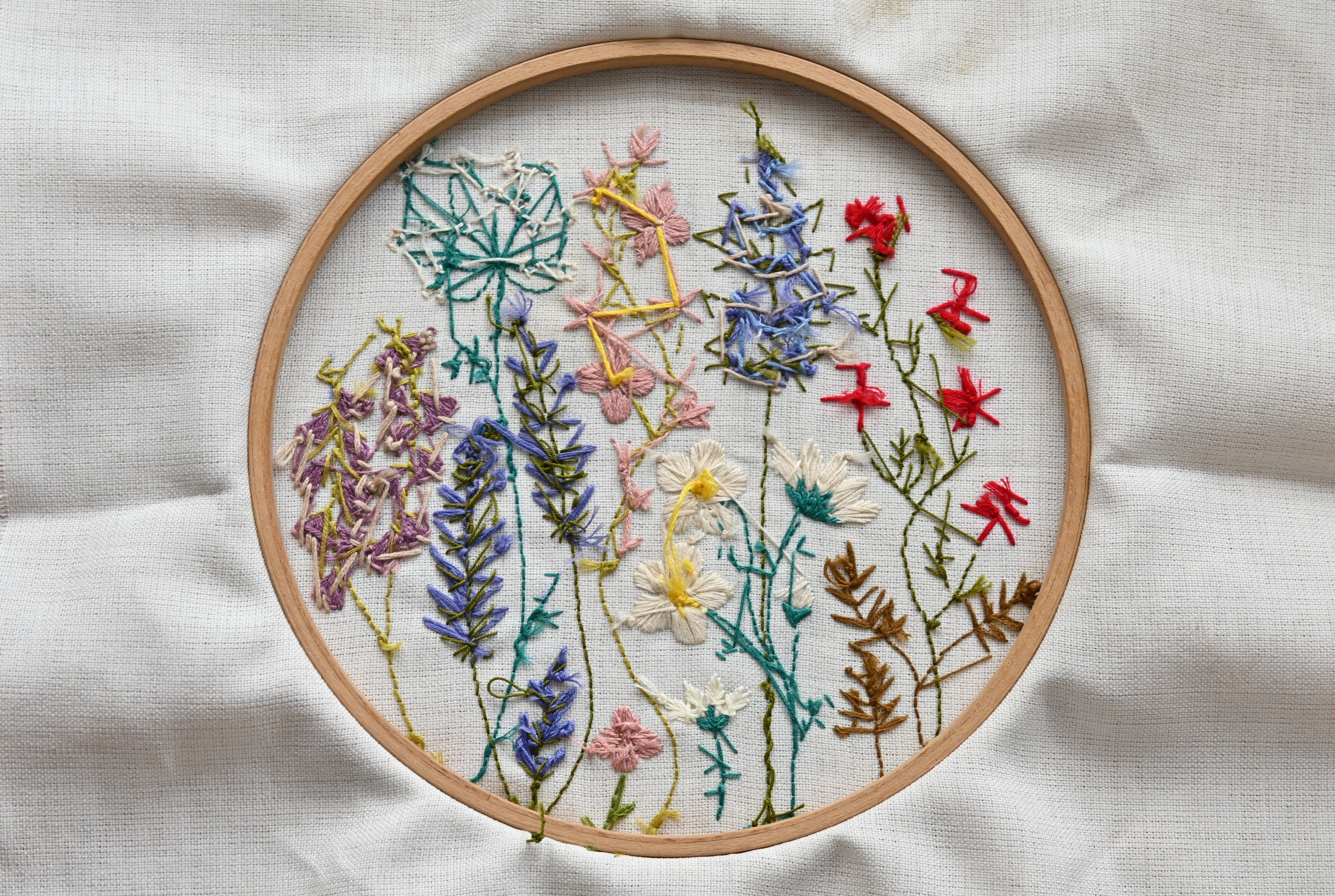 Vibrant needlework of wildflowers on fabric in a wooden hoop.